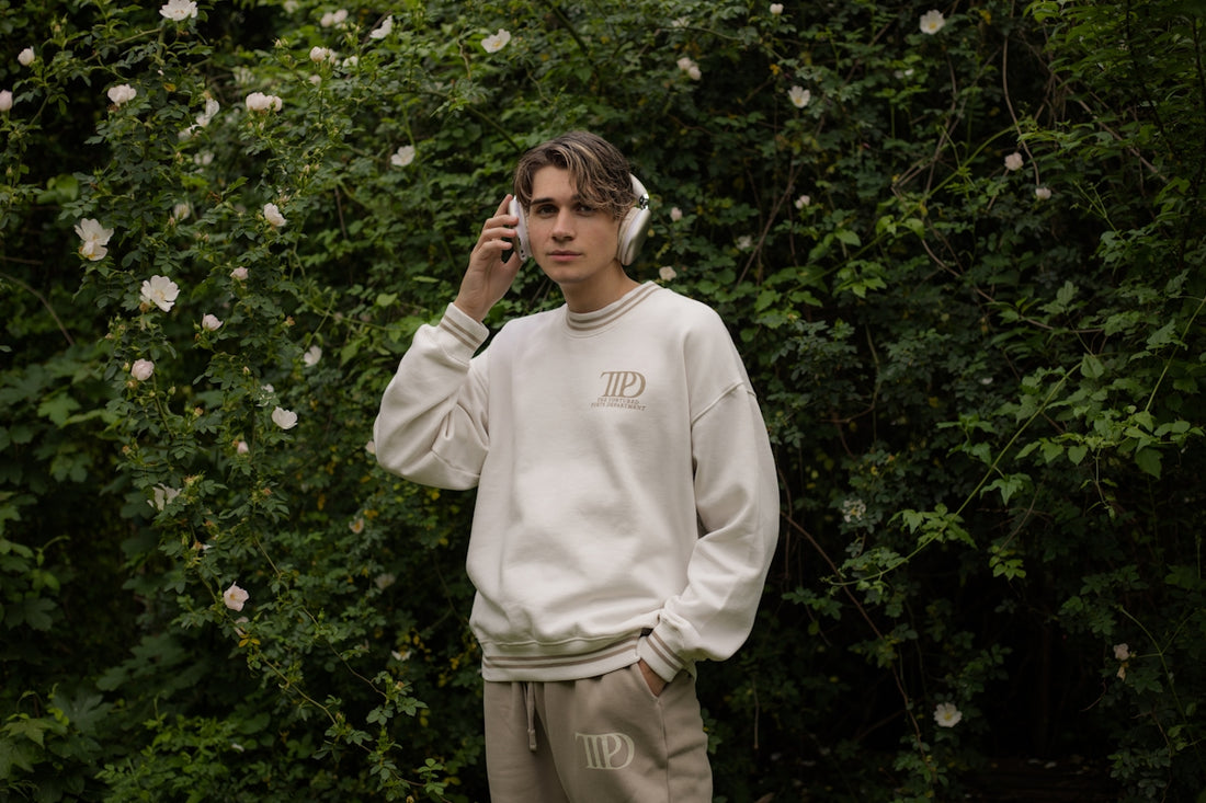 Young man poses in front of a flowery bush.